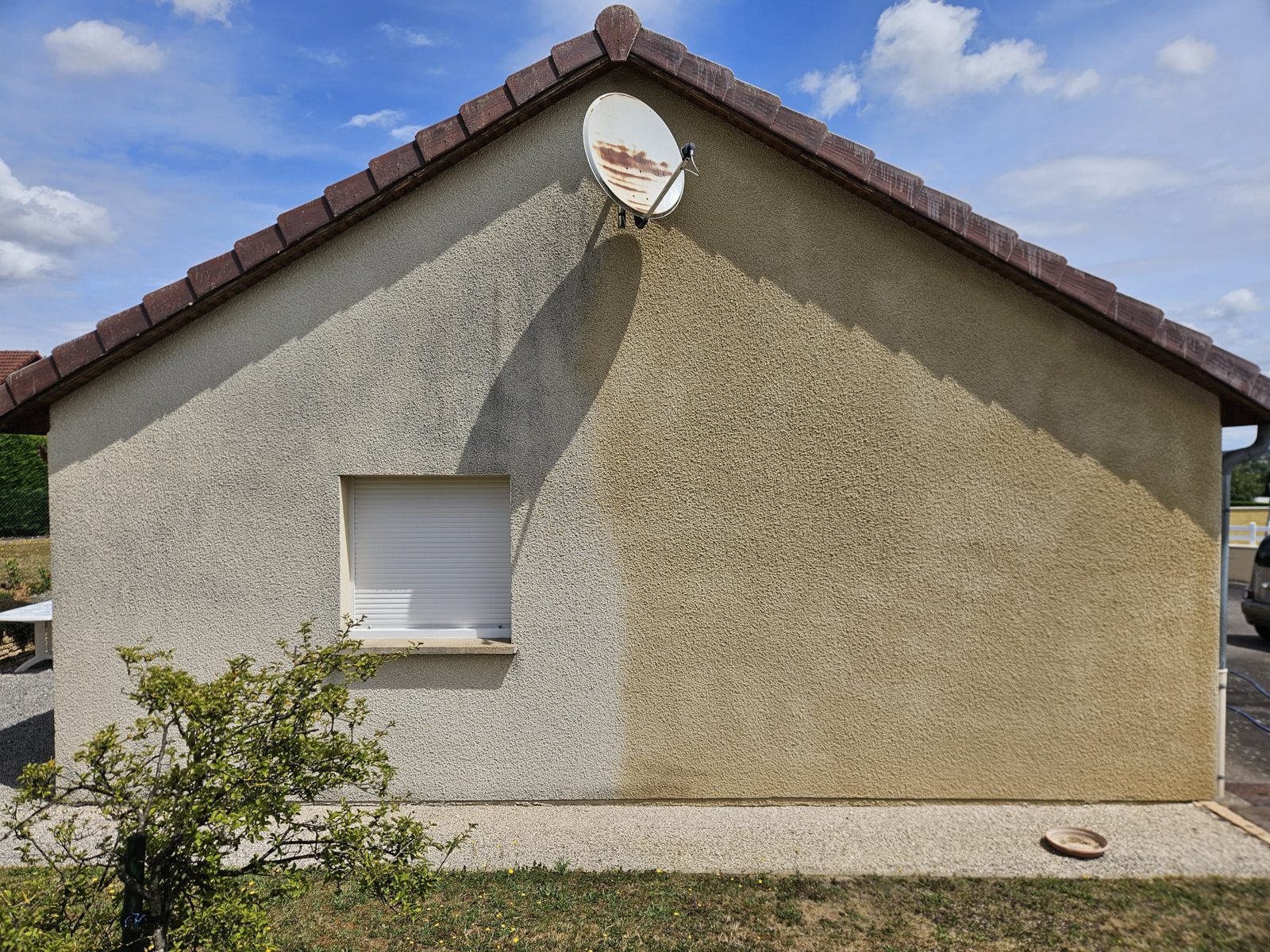 Pignon nettoyé à moitié : à gauche le crépi gris, à droite le crépi beige retrouvé.