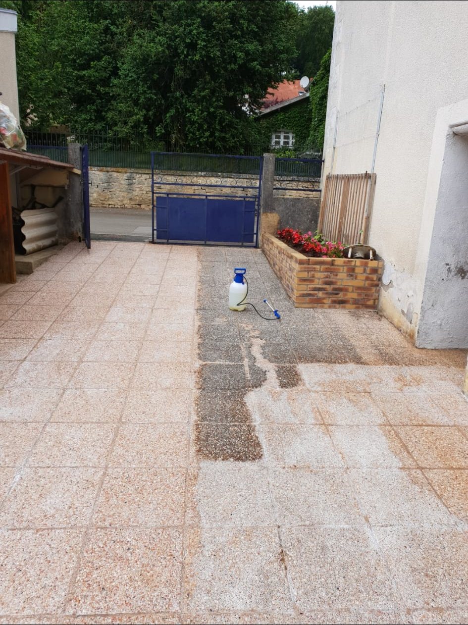 Terrasse carrelée nettoyée en partie : une bande encore sale au milieu du carrelage clair.