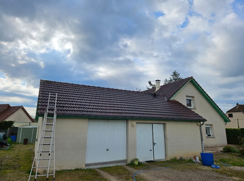 Avant : maison et garage, toiture sombre, une échelle contre le mur.